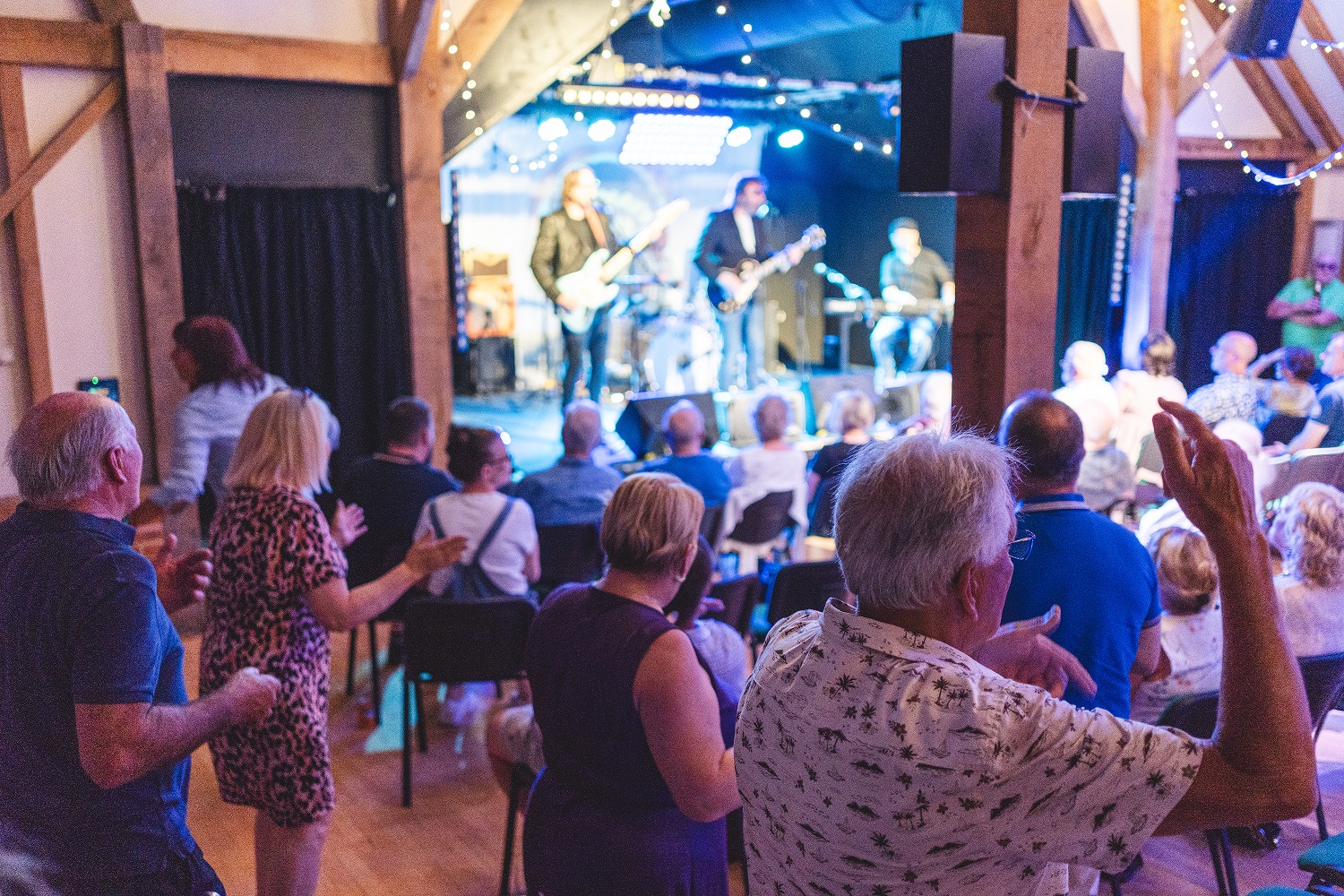 Audience dancing in the aisles with band playing in the background.