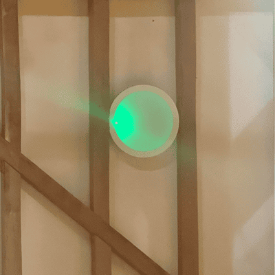 New round LED wall light switched on and glowing at Hanger Farm Arts Centre. Light is surrounded by wooden beams